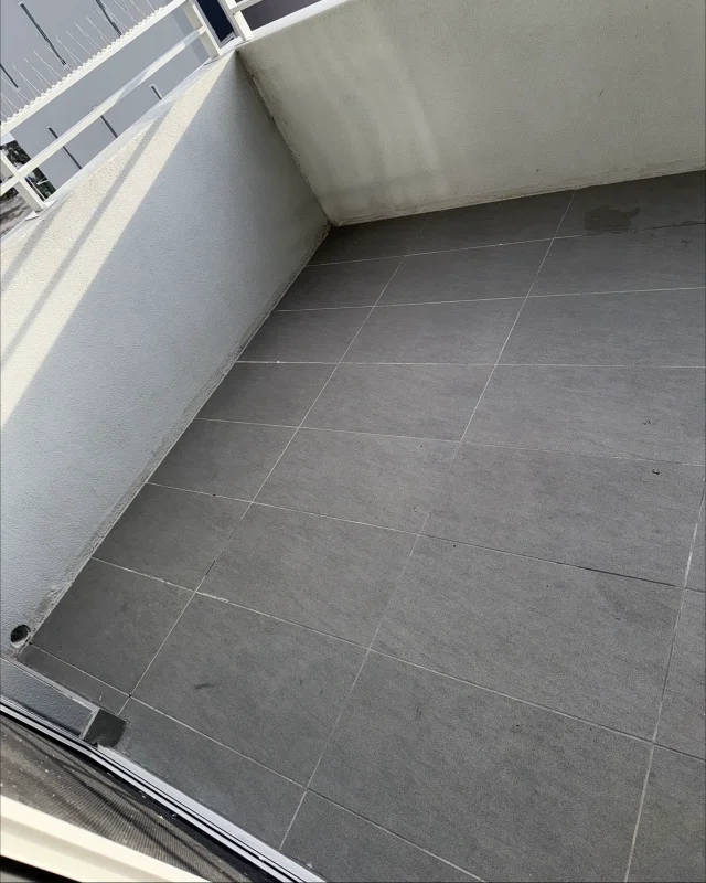 The same balcony floor pressure cleaned, the tile faces and grout lines back to even grey