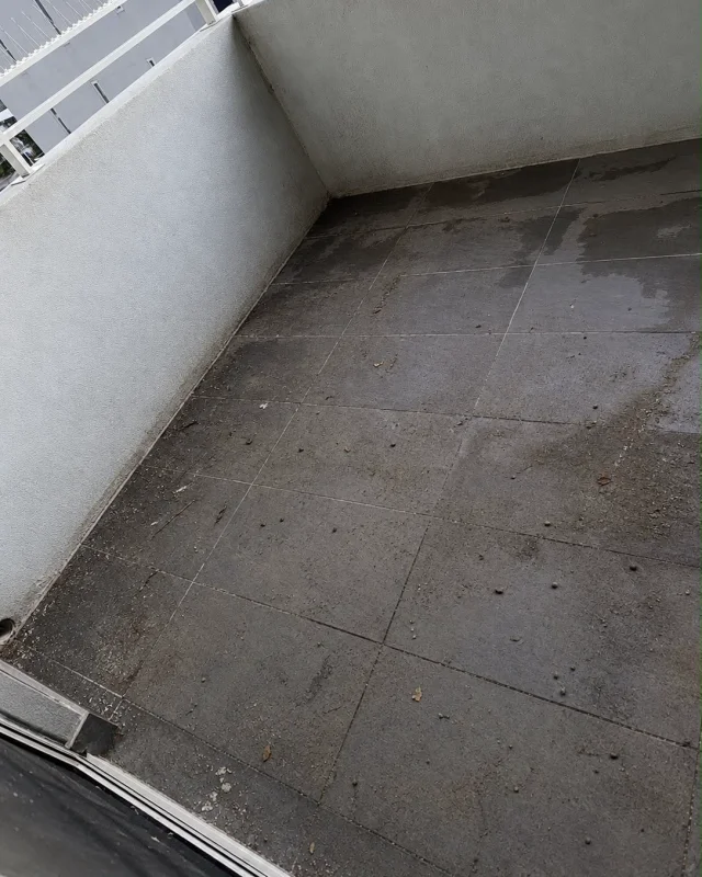 Balcony floor tiles darkened with ingrained grime, leaf litter and droppings before pressure cleaning