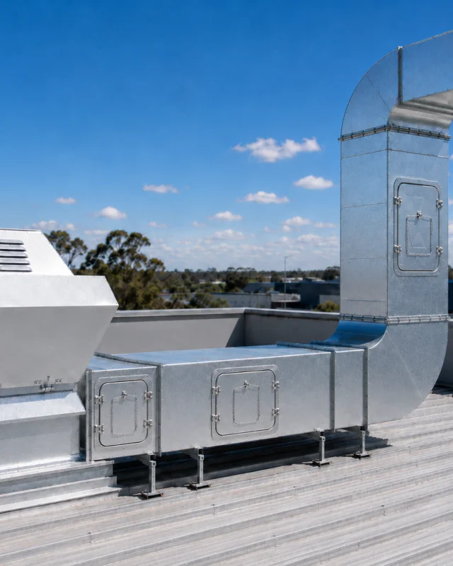 Rooftop exhaust ductwork with hinged access panels fitted along the horizontal run and on the vertical riser